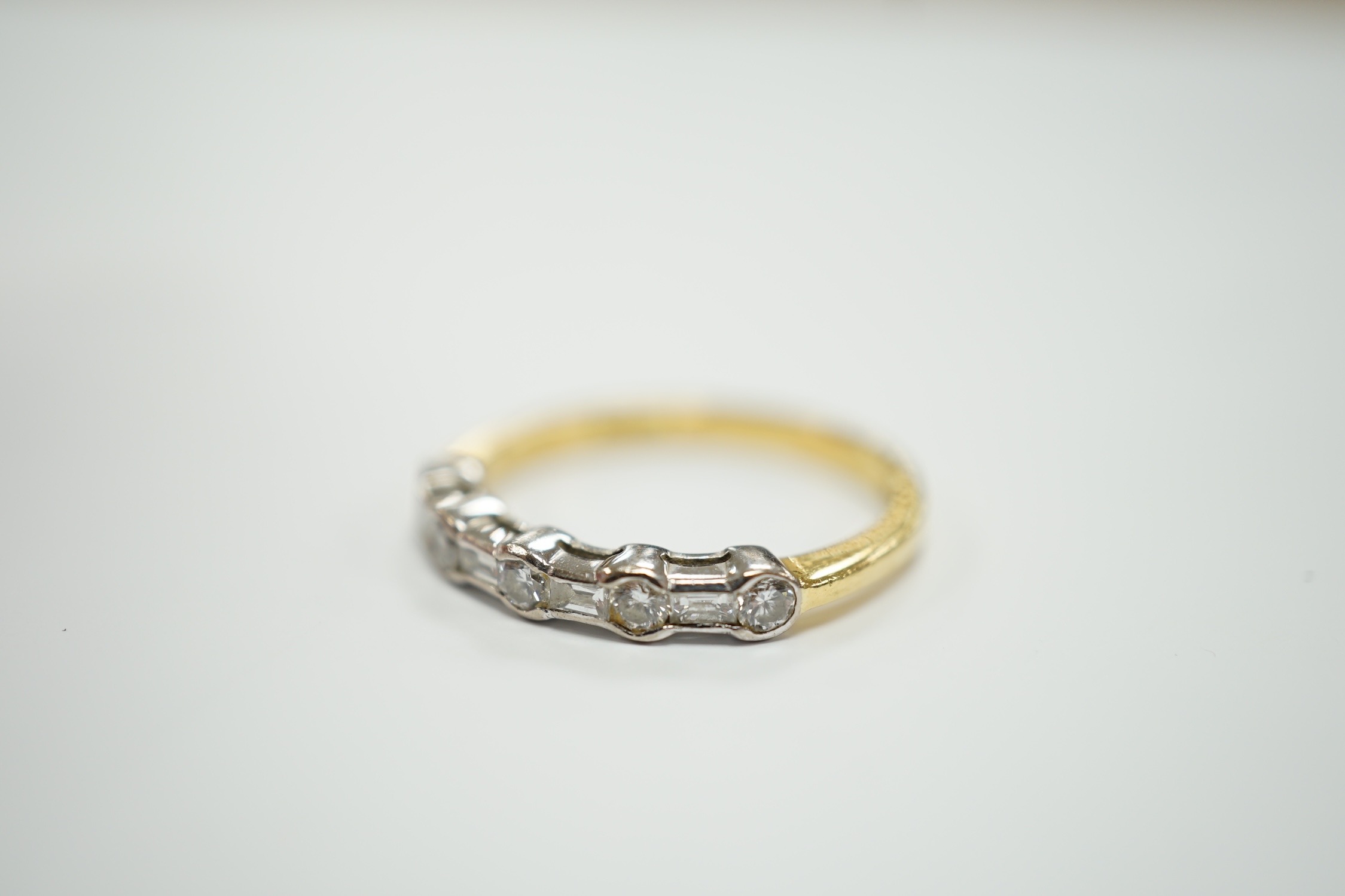 A modern 18ct gold, round and baguette cut diamond set half hoop ring, size N/O, gross weight 3.2 grams.